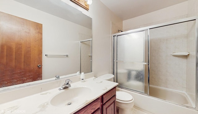 full bathroom with enclosed tub / shower combo, vanity, and toilet