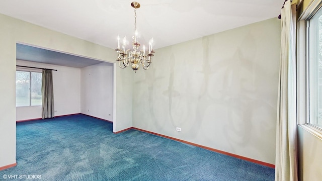 carpeted spare room with an inviting chandelier and a wealth of natural light