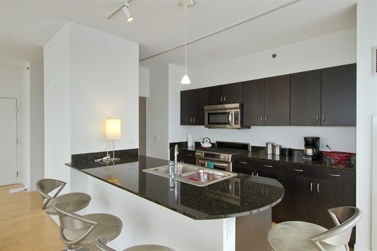 kitchen featuring a kitchen breakfast bar, sink, stainless steel appliances, and decorative light fixtures