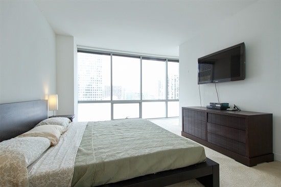 bedroom featuring light carpet and floor to ceiling windows