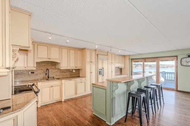 kitchen featuring a center island, sink, light hardwood / wood-style floors, cream cabinetry, and a breakfast bar area