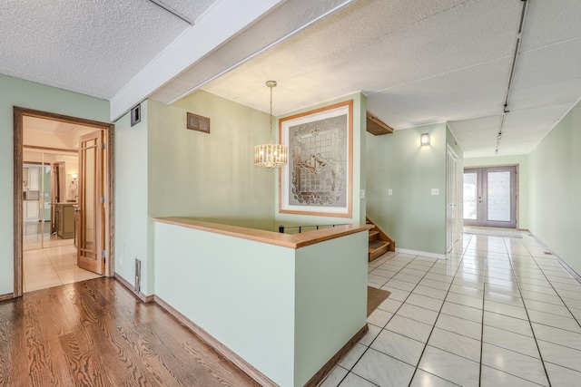 hallway featuring french doors, rail lighting, a notable chandelier, and light hardwood / wood-style flooring