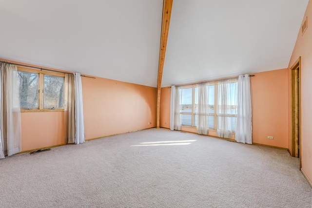 unfurnished room with vaulted ceiling with beams, light colored carpet, and a healthy amount of sunlight