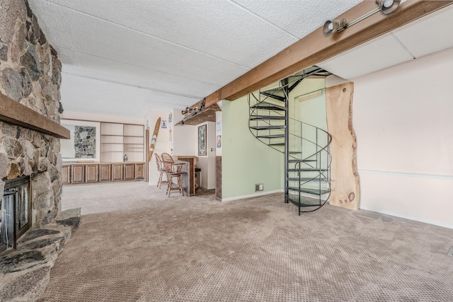 unfurnished living room with a fireplace, built in shelves, carpet floors, and a textured ceiling