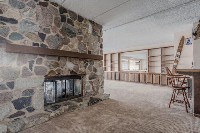 carpeted living room featuring a stone fireplace and a textured ceiling