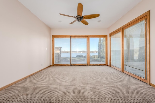 unfurnished sunroom featuring ceiling fan and a water view