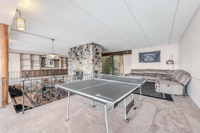 recreation room featuring carpet flooring, a stone fireplace, and a textured ceiling