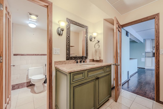 bathroom with tile patterned flooring, vanity, tile walls, and toilet