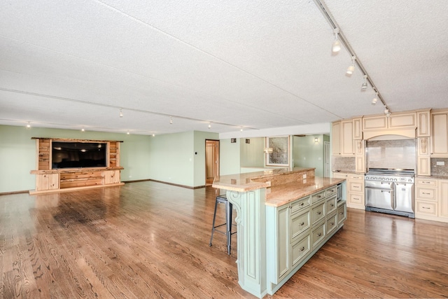 kitchen with backsplash, light stone counters, a breakfast bar, stainless steel appliances, and a spacious island