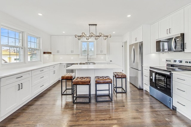 kitchen with a breakfast bar, appliances with stainless steel finishes, white cabinetry, and a kitchen island