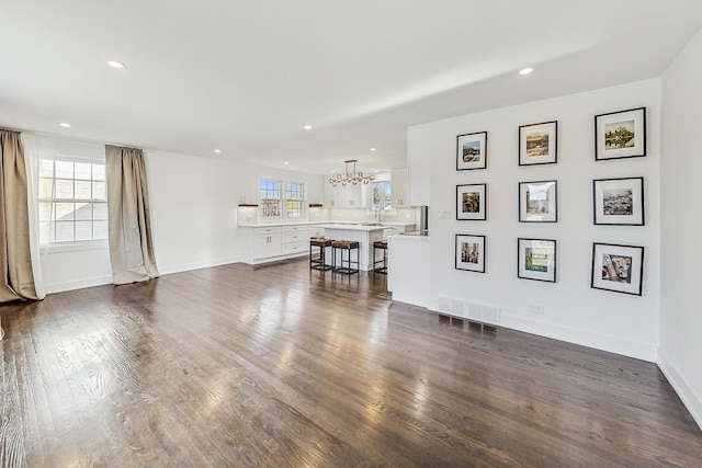 unfurnished living room featuring dark hardwood / wood-style flooring and an inviting chandelier