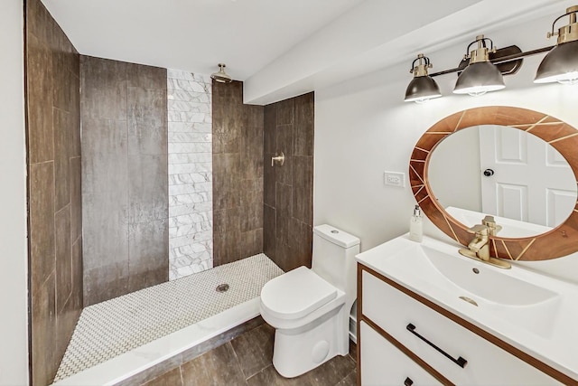 bathroom with a tile shower, vanity, and toilet