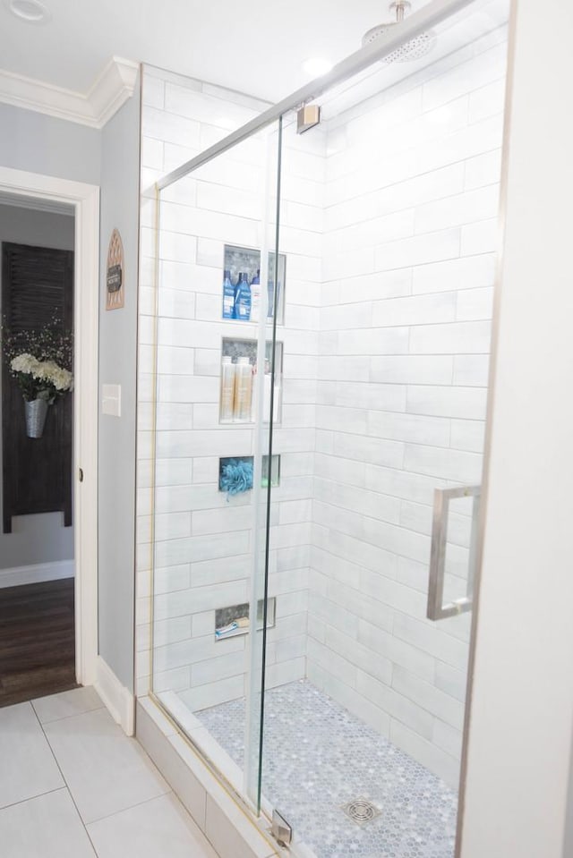 bathroom with tile patterned flooring, a shower with shower door, and ornamental molding