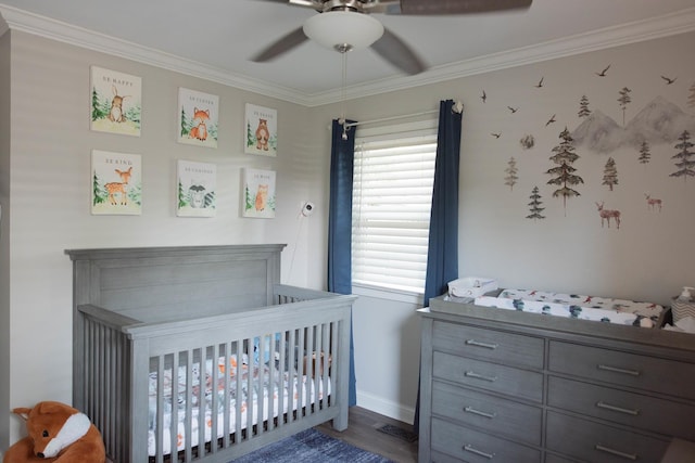 bedroom with ceiling fan, dark hardwood / wood-style flooring, ornamental molding, and a nursery area