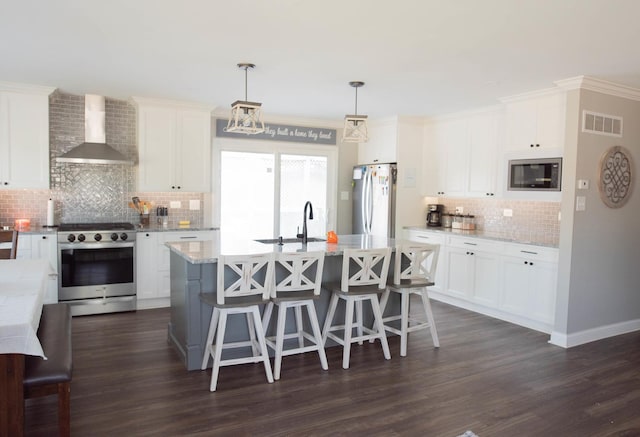 kitchen featuring white cabinets, hanging light fixtures, wall chimney exhaust hood, and stainless steel appliances