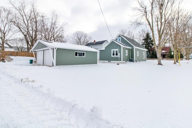 snow covered rear of property with a garage and an outbuilding