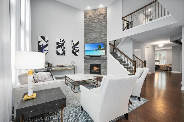 living room with a fireplace, a high ceiling, and wood-type flooring