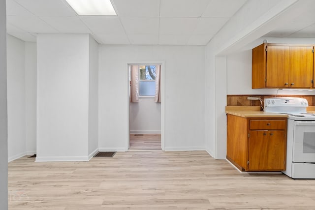 kitchen with white electric range oven, a drop ceiling, and light wood-type flooring