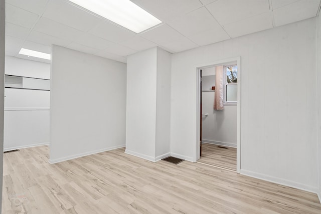 unfurnished room featuring a drop ceiling and light wood-type flooring