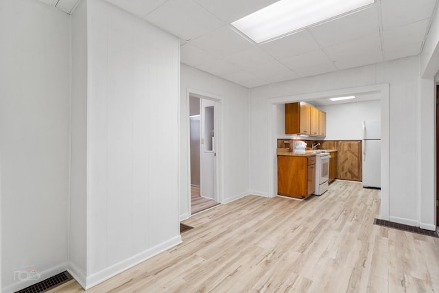 kitchen with a drop ceiling, light hardwood / wood-style floors, and white appliances