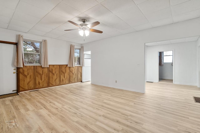 empty room featuring a drop ceiling, light hardwood / wood-style floors, and ceiling fan