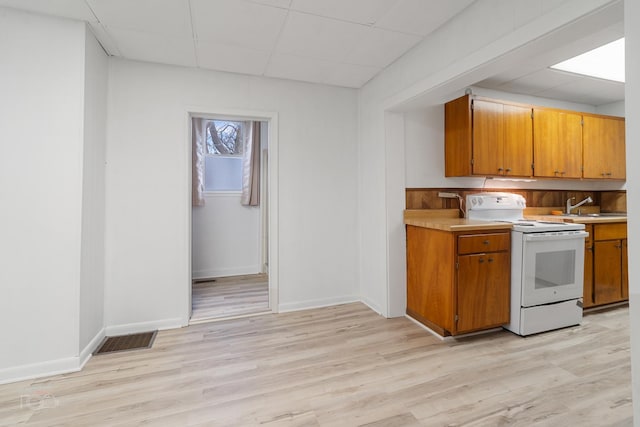 kitchen featuring a drop ceiling, sink, light hardwood / wood-style floors, and electric range