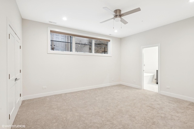 unfurnished bedroom with ceiling fan, light colored carpet, and ensuite bathroom