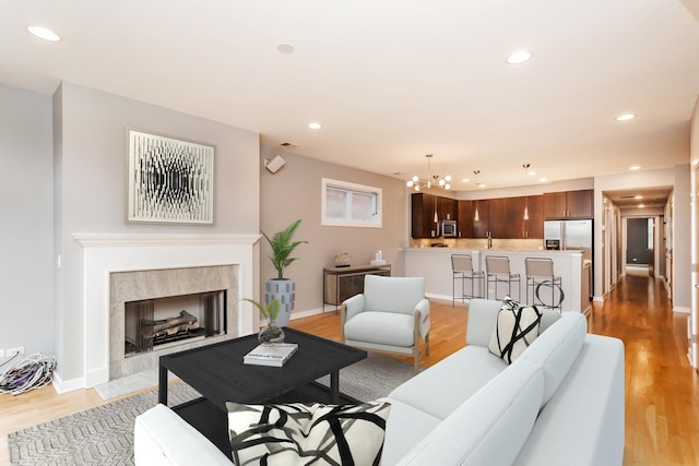 living room with an inviting chandelier, a multi sided fireplace, and light hardwood / wood-style floors