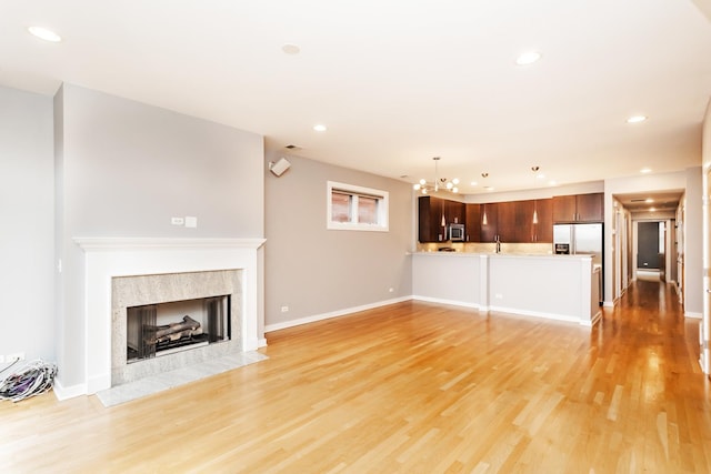 unfurnished living room featuring light wood-type flooring and a chandelier