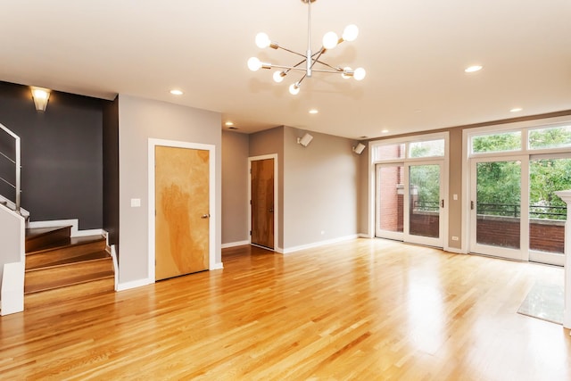 unfurnished living room featuring an inviting chandelier and light hardwood / wood-style flooring