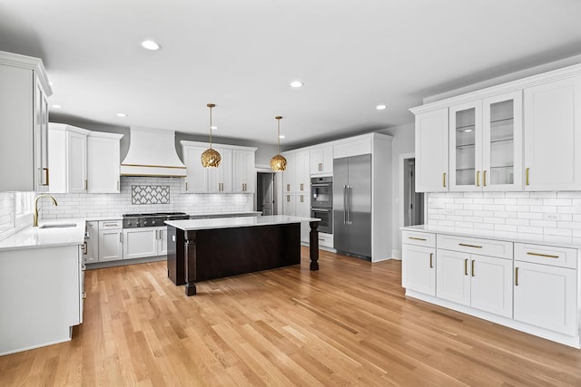 kitchen featuring sink, a center island, custom range hood, stainless steel appliances, and white cabinets