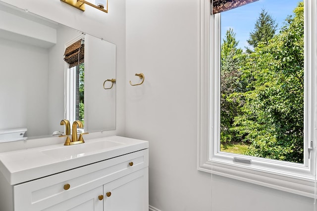 bathroom with vanity, toilet, and a healthy amount of sunlight