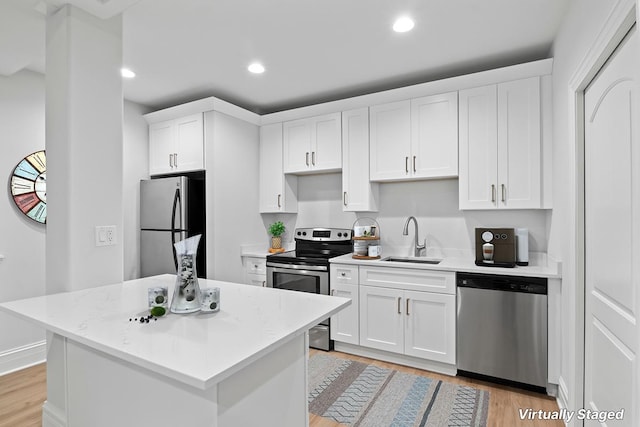 kitchen featuring appliances with stainless steel finishes, sink, white cabinets, a center island, and light stone counters