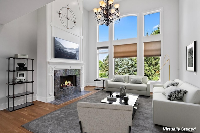 living room with a high ceiling, a healthy amount of sunlight, dark hardwood / wood-style floors, and a fireplace