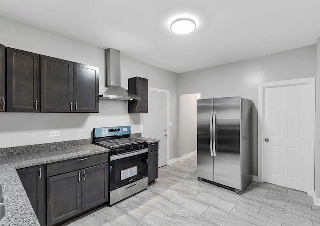 kitchen with dark brown cabinets, light stone counters, wall chimney range hood, and stainless steel appliances