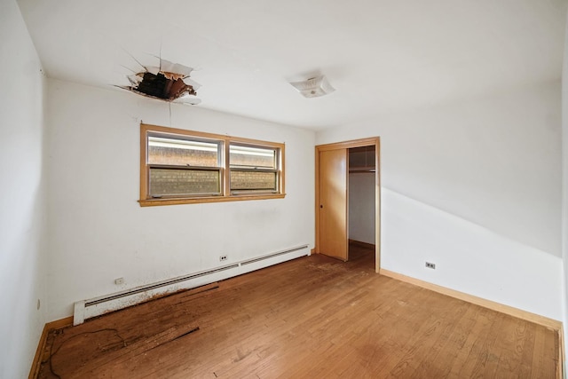 unfurnished bedroom with a closet, light hardwood / wood-style flooring, and a baseboard radiator