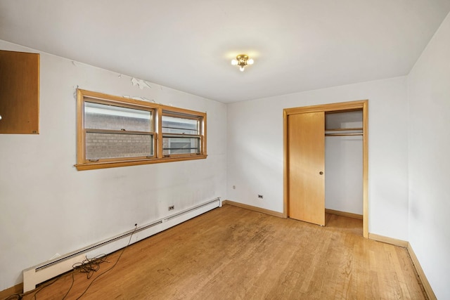 unfurnished bedroom featuring light hardwood / wood-style flooring, a closet, and a baseboard heating unit