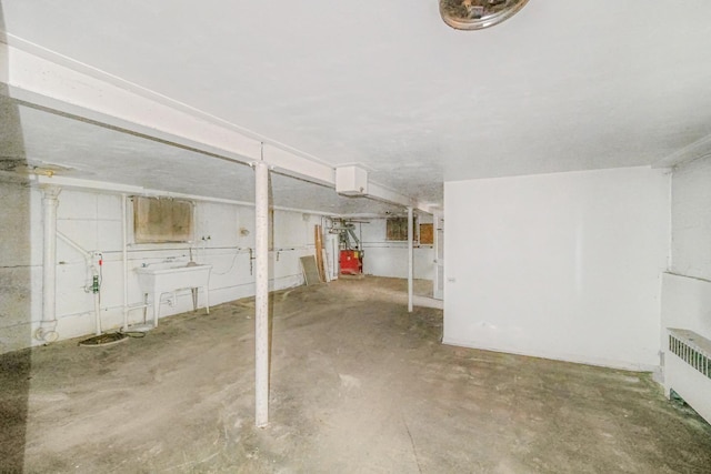 basement featuring gas water heater, sink, and radiator