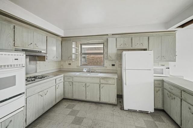 kitchen featuring white appliances, backsplash, and sink