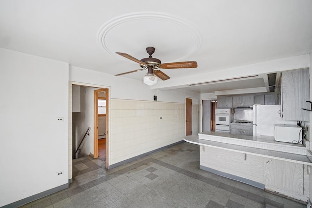 interior space with ceiling fan, white appliances, and kitchen peninsula