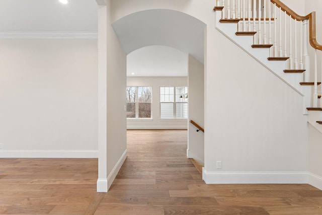 hallway with ornamental molding and light hardwood / wood-style flooring