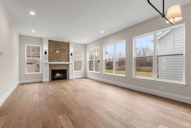 unfurnished living room featuring light wood-type flooring and a stone fireplace