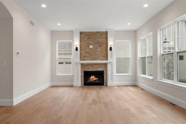 unfurnished living room featuring light wood-type flooring and a large fireplace