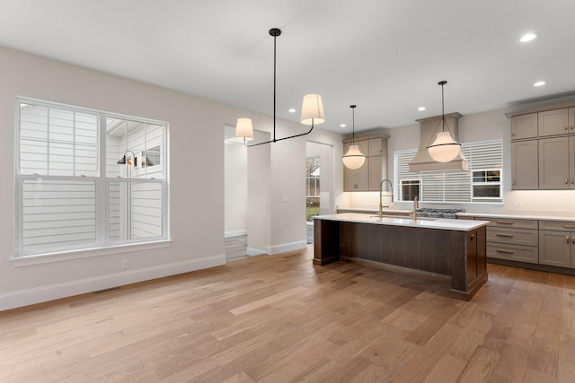 kitchen with a center island with sink, pendant lighting, and light wood-type flooring