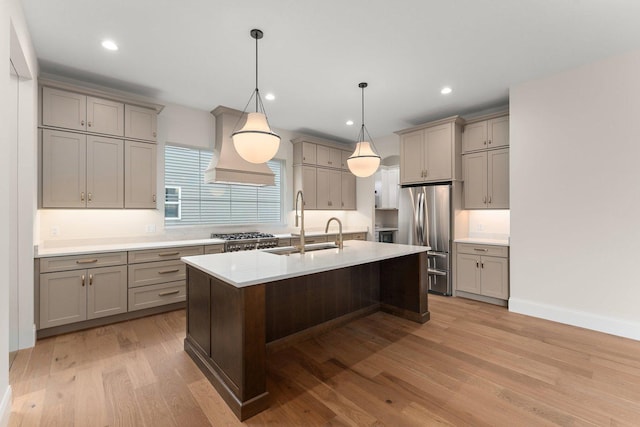 kitchen featuring stainless steel fridge, custom range hood, pendant lighting, light hardwood / wood-style floors, and a breakfast bar area