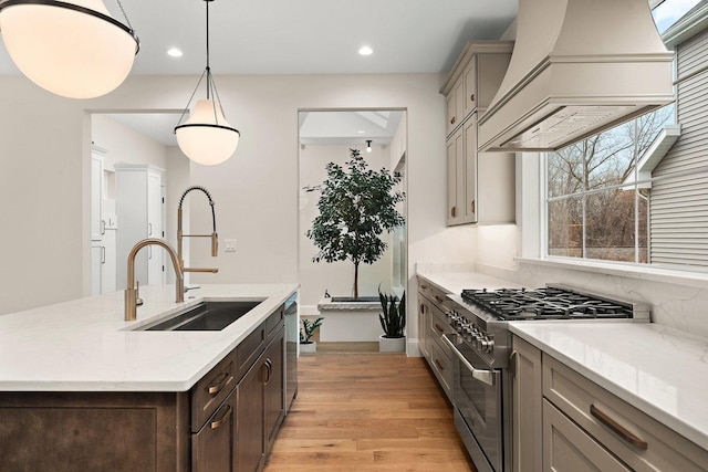 kitchen with light stone countertops, custom range hood, stainless steel appliances, sink, and pendant lighting