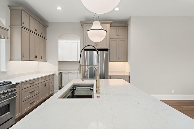 kitchen featuring decorative light fixtures, sink, light stone counters, and stainless steel appliances