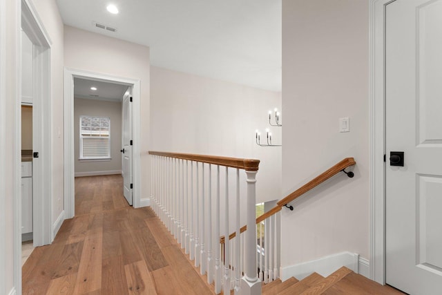 corridor with a chandelier and light hardwood / wood-style floors