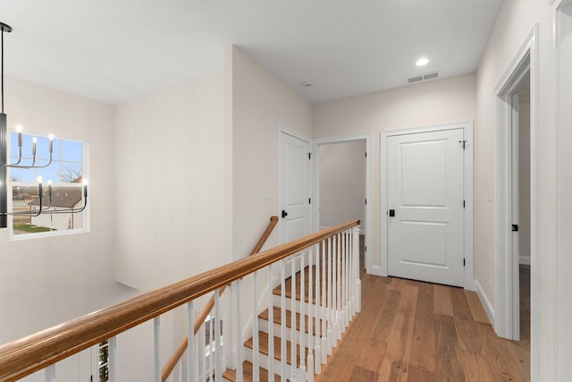 hallway with light wood-type flooring and a chandelier