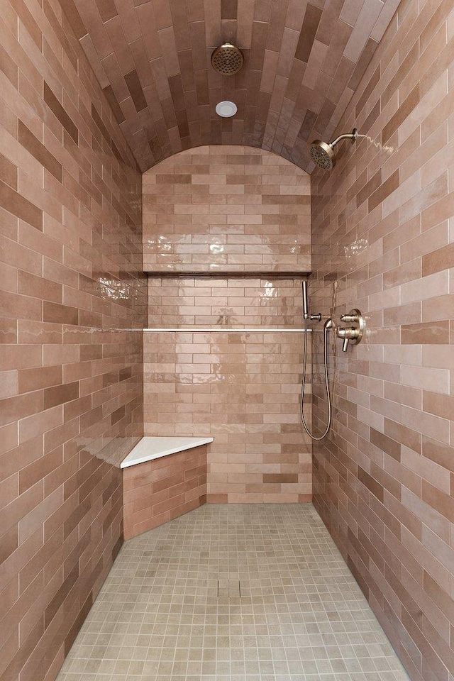 bathroom featuring a tile shower, vaulted ceiling, and brick ceiling